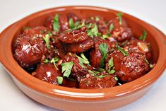 an orange bowl filled with meat covered in sauce