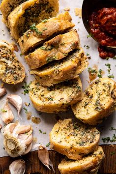 garlic bread sliced up on a cutting board next to some garlic and pepper sauces