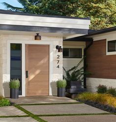 the front door of a house with two planters on each side and numbers on the wall