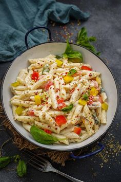 a white bowl filled with pasta and vegetables on top of a blue table cloth next to a