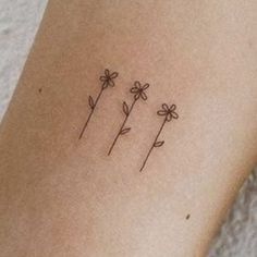 three daisies tattoo on the left side of the leg, with one flower in it's center