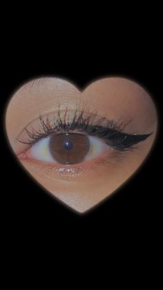 an eye with long lashes is seen through a heart