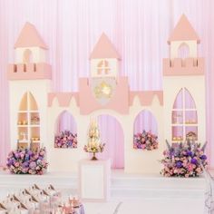 there is a pink and white castle with flowers on the table in front of it