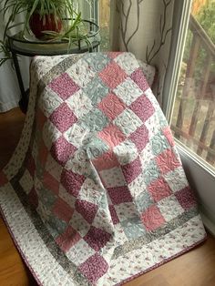 a quilted blanket sitting on top of a window sill next to a potted plant