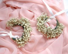 two wreaths are laying on a pink fabric