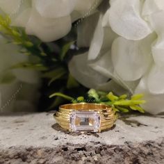 a close up of a ring on top of a rock with flowers in the background