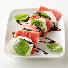 slices of watermelon and basil on a white plate