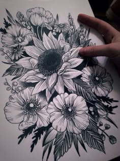 a drawing of flowers in black and white on paper with a person's hand