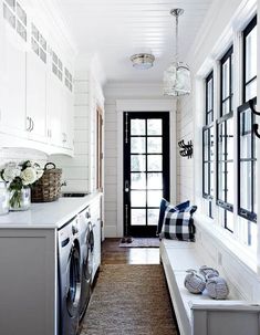 a washer and dryer in a room with white walls, wood flooring and black door