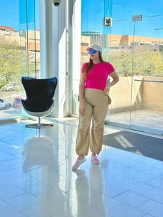 a woman in pink shirt and khaki pants posing for the camera