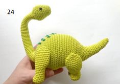 a crocheted green toy dinosaur in the palm of someone's hand