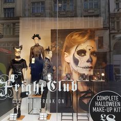 a display case with halloween costumes and makeup on it's sides in front of a building