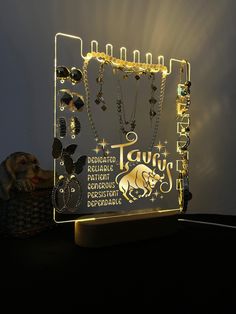 a lighted display with jewelry on it and a cat sitting next to it in the background