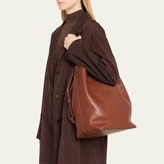 THE ROW "Belvedere" bucket bag in saddle leather  Shoulder strap  Drawstring closure  Interior, one zip pocket  Approx. 7.1"H x 14.8"W x 11.8"D Made in Italy Brown Bag, Saddle Leather, Brown Bags, Saddle, Bucket Bag, The Row, Zip Pockets, Tops Designs, Shoulder Strap