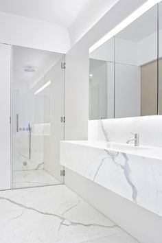 a bathroom with marble counter tops and white walls, along with a walk in shower