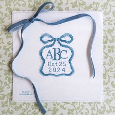 a blue ribbon tied around a white card with the words abc and date on it