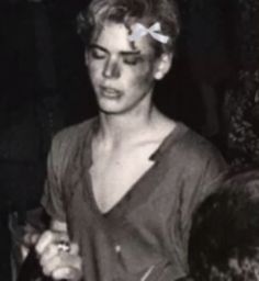 black and white photo of woman with bow in hair looking at something on her face