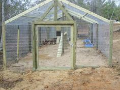 an outdoor chicken coop in the middle of a dirt area with stairs leading up to it