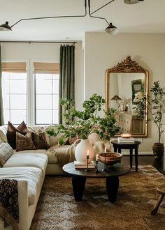 a living room filled with furniture and a large mirror on the wall above it's windows