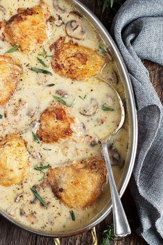 a pan filled with chicken and mushrooms covered in gravy on top of a wooden table