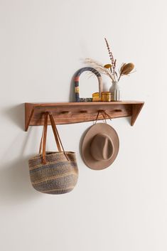 a hat and purse hanging on a wooden shelf next to a wall mounted coat rack