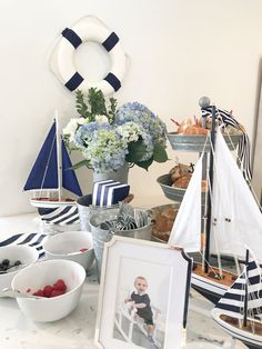 a table topped with pictures and boats on top of it's countertop next to a vase filled with flowers