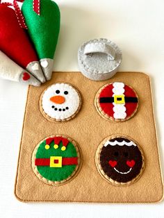 decorated cookies are sitting on a mat next to some felt santa hats and snowmen