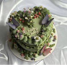 a heart shaped cake with flowers and butterflies on it's top, sitting on a white table cloth