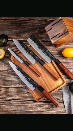 five knives are on a cutting board next to an avocado and lemons