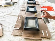 a person is spray painting some frames on the table with white paint and brown paper