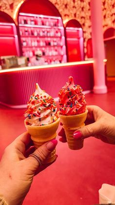 two ice cream cones with sprinkles are being held in front of the camera