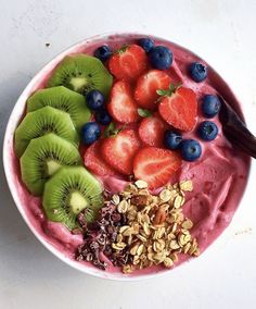 a bowl filled with fruit and granola on top of a table