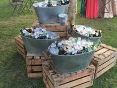 three buckets filled with beer bottles sitting on top of wooden pallets in the grass