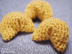 three yellow crocheted elephants sitting on top of a blue cloth