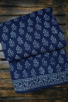 two pieces of blue and white cloth on top of a wooden table next to each other