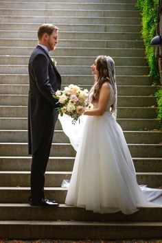 a bride and groom standing on the steps