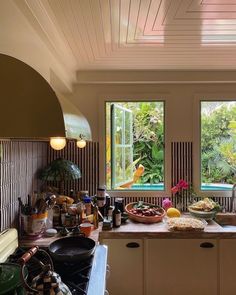 a kitchen filled with lots of clutter next to two large windows that look out onto the jungle