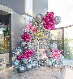 the balloon arch is decorated with pink and silver balloons