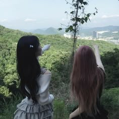 two young women looking at the view from a high viewpoint point on a hill top