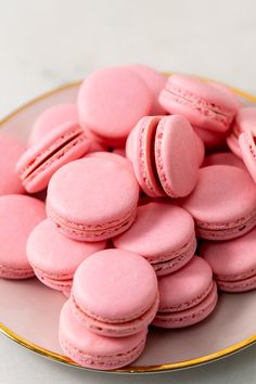 a plate full of pink macaroons on a table