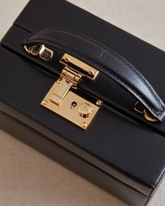 The 1845 Trunk is a replica of an original Mark Cross design from 1904. This top handle box bag features a push lock closure, adjustable chain and leather crossbody strap and is lined in our iconic MC Red Italian calfskin. Timeless Formal Bag With Lock, Timeless Formal Bags With Lock, Timeless Briefcase With Gold-tone Hardware, Designer Formal Briefcase With Gold-tone Hardware, Designer Briefcase With Gold-tone Hardware For Formal Occasions, Classic Gift Bags With Gold-tone Hardware, Luxury Rectangular Briefcase With Gold-tone Hardware, Classic Everyday Luxury Bag With Rectangular Case, Luxury Briefcase With Gold-tone Hardware