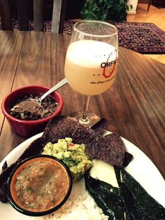 a white plate topped with food next to a bowl of soup and a glass of beer