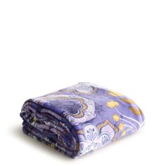 the purple and gold paisley print blanket is folded on top of it's side