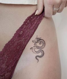 a woman with a dragon tattoo on her stomach is holding onto the side of her thigh