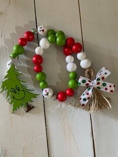 a christmas wreath made out of balloons and other decorations on a white wooden surface with a green tree ornament