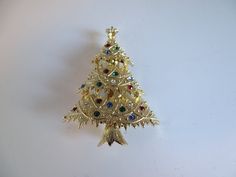 "This Eisenberg Ice red, green, and blue faceted rhinestone Christmas tree brooch pin is o a gold tone setting and is just beautiful.  The gold tone setting has textured pine boughs. This brooch is signed Eisenberg Ice.  This piece is in excellent vintage condition (see photos). This piece measures approximately  2-1/4\" by 1-5/8\".  Our jewelry comes boxed, ready for gifting (if you can part with this beautiful piece). Don't forget to Favorite our shop so you can find us again as we are always adding new items. We'd love to have you follow us at: Facebook - www.facebook.com/SecondWindVintageShop/. Pinterest - www.pinterest.com/SecondWindShop Instagram - @SecondWindVintageShop We do our absolute best to research and identify items correctly and do our best to point out and identify any iss Gold Brooches For Christmas Gift, Gold Christmas Brooches For Formal Wear, Gold Brooches For Formal Christmas Occasion, Gold Holiday Brooch Jewelry, Gold Christmas Holiday Brooch, Holiday Formal Jewelry Brooch, Elegant Gold Christmas Brooches, Holiday Formal Brooch Jewelry, Formal Christmas Brooch Jewelry