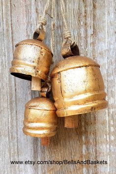 two brass bells hanging on a wooden wall