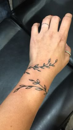 a woman's hand with a small tattoo on her left wrist and an olive branch in the middle