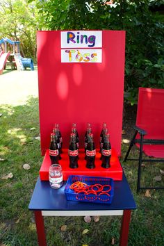 a table that has some soda bottles on it and a sign reading ring tosses