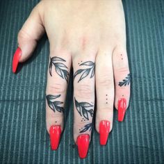 a woman's hand with red fingernails and tattoos on it